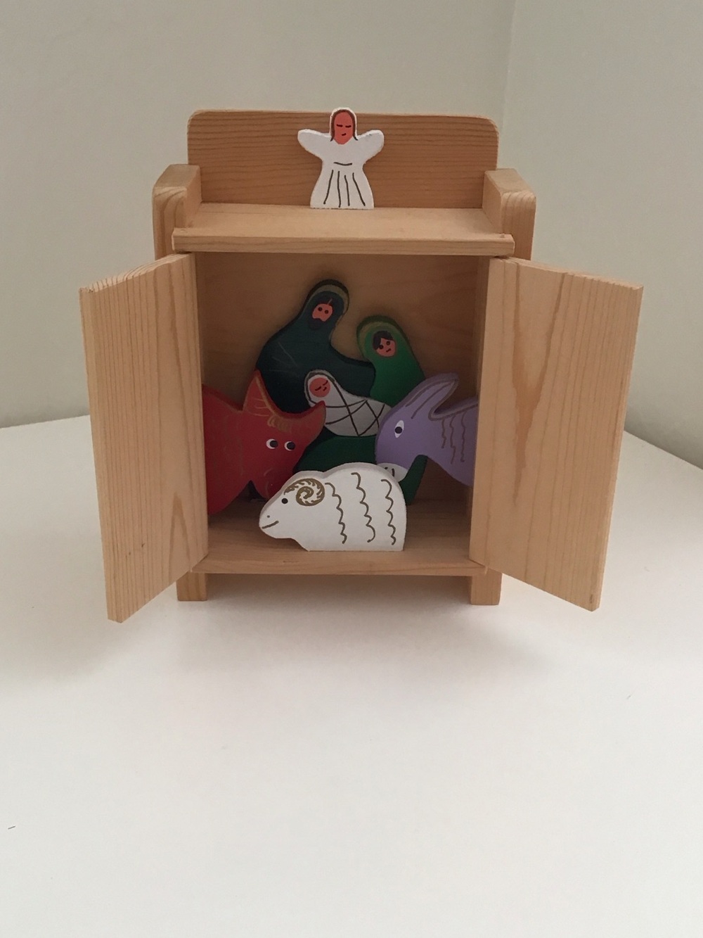 Handmade wooden cabinet holding a small wooden Nativity set
